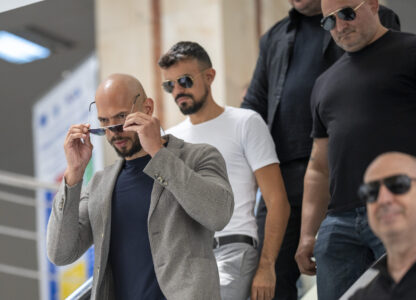 Andrew Tate leaves the Bucharest Tribunal along with his bodyguards after the first hearing his trial, meant to establish if he and his brother Tristan will remain under house arrest, in Bucharest, Romania, Wednesday, June 21, 2023. Romanian prosecutors charged on Tuesday, June 20, 2023, the Tate brothers and two other suspects with human trafficking, rape and organizing a criminal group for the sexual exploitation of women. (AP Photo/Vadim Ghirda)