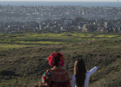 People look at buildings that were destroyed during the Israeli air and ground offensive stand in the Gaza Strip as seen from southern Israel, Sunday, March 2, 2025. (AP Photo/Leo Correa)