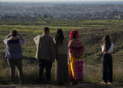 People look at buildings that were destroyed during the Israeli air and ground offensive stand in the Gaza Strip as seen from southern Israel, Sunday, March 2, 2025. (AP Photo/Leo Correa)