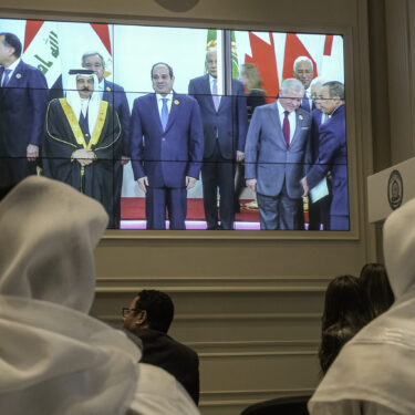 Journalists watch a screen displaying Egyptian President Abdel Fattah el-Sissi, center, with Arab Leaders, at the press center hall of the emergency Arab summit at Egypt's New Administrative Capital, just outside Cairo, Tuesday, March 4, 2025. (AP Photo/Amr Nabil)