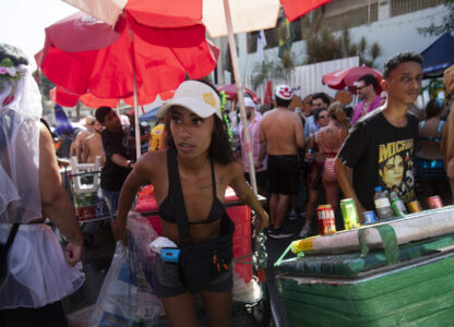 A vendor pulls through a crowd of revelers a cart carrying a cooler of ice cold beverages at the Heaven on Earth pre-Carnival street party, in Rio de Janeiro, Saturday, Feb. 22, 2025. (AP Photo/Bruna Prado)