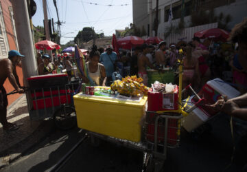 Vendors push Styrofoam coolers through a crowd of revelers at the Heaven on Earth pre-Carnival street party, in Rio de Janeiro, Saturday, Feb. 22, 2025. (AP Photo/Bruna Prado)