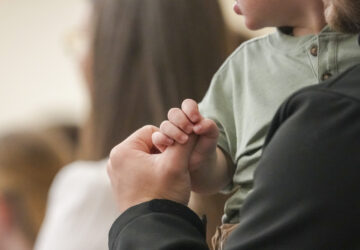 A child holds a man's finger during a service at Community Church of Seminole, Sunday, Feb. 23, 2025, in Seminole, Texas. (AP Photo/Julio Cortez)