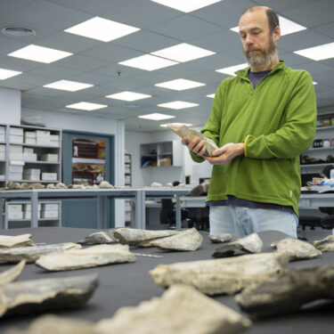 In this photo provided by the Spanish National Research Council (CSIC), researcher Ignacio de la Torre holds a bone tool found in Tanzania's Olduvai Gorge, at the CSIC-Pleistocene Archaeology Lab in Madrid in 2023. (Angeliki Theodoropoulou/CSIC via AP)