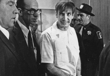 FILE - Convicted murderer Gary Mark Gilmore arrives, heavily guarded, at the 4th District Court in Provo, Utah, on Dec. 1, 1976. (AP Photo/Ron Barker, File)