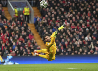 Liverpool's goalkeeper Alisson dives for the ball during the Champions League round of 16 second leg soccer match between Liverpool and Paris Saint-Germain at Anfield in Liverpool, England, Tuesday, March 11, 2025. (AP Photo/Jon Super)