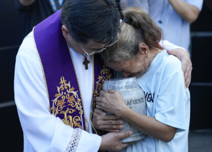 Filipino Catholic priest Flavie Villanueva, left, consoles Melinda Lafuente, as she holds the urn containing the remains of her son Angelo, during an interment ceremony for victims of extrajudicial killings, at the 