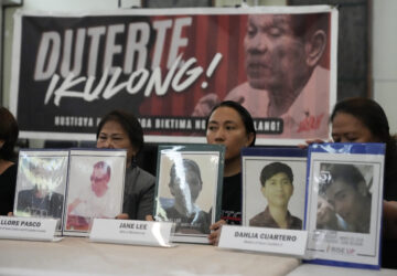 Relatives hold pictures of victims of alleged extra-judicial killings in front of a picture arrested former Philippine president Rodrigo Duterte with a sign that says 