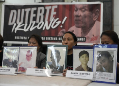 Relatives hold pictures of victims of alleged extra-judicial killings in front of a picture arrested former Philippine president Rodrigo Duterte with a sign that says 