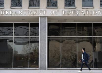 A commuter walks past the headquarters of the U.S. Department of Eduction, which were ordered closed for the day for what officials described as security reasons amid large-scale layoffs, Wednesday, March 12, 2025, in Washington. (AP Photo/Mark Schiefelbein)