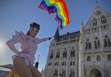 FILE - A participant waves a rainbow flag during an LGBT rights demonstration in front of the Hungarian Parliament building in Budapest, Hungary on June 14, 2021. (AP Photo/Bela Szandelszky, File)