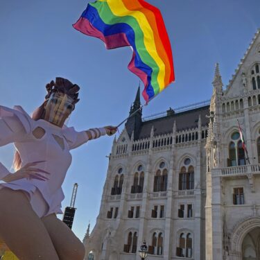FILE - A participant waves a rainbow flag during an LGBT rights demonstration in front of the Hungarian Parliament building in Budapest, Hungary on June 14, 2021. (AP Photo/Bela Szandelszky, File)