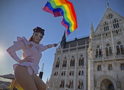 FILE - A participant waves a rainbow flag during an LGBT rights demonstration in front of the Hungarian Parliament building in Budapest, Hungary on June 14, 2021. (AP Photo/Bela Szandelszky, File)