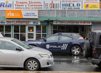 A police car patrols a street in front of a liquor store in Barrio Obrero, San Juan, Puerto Rico, Friday, March 14, 2025. (AP Photo/Alejandro Granadillo)