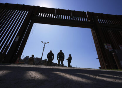 Border Patrol agents and members of the military stand inside a gate in one of two border walls separating Mexico from the United States during a news conference on joint operations involving the military and the Border Patrol, Friday, March 21, 2025, in San Diego. (AP Photo/Gregory Bull)