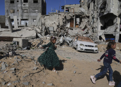 Palestinian girls dressed for Eid al-Fitr celebrations walk next to destructions in Jabaliya, Gaza Strip on Monday, March 31, 2025. (AP Photo/Jehad Alshrafi)