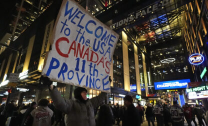FILE - As fans enter the Boston Garden, a man holds a sign on the sidewalk prior to the 4 Nations Face-Off championship hockey game between the United States and Canada,Feb. 20, 2025, in Boston. (AP Photo/Charles Krupa, File)