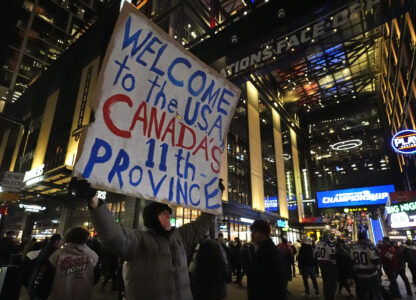 FILE - As fans enter the Boston Garden, a man holds a sign on the sidewalk prior to the 4 Nations Face-Off championship hockey game between the United States and Canada,Feb. 20, 2025, in Boston. (AP Photo/Charles Krupa, File)