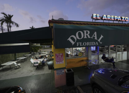 U.S. citizens who immigrated from Venezuela between 16 and 30 years ago play dominos outside El Arepazo, a restaurant that is a hub of the largest Venezuelan community in the U.S., in Doral, Fla., Wednesday, April 2, 2025. Many of the friends, including Cesar Mena, at right, voted for President Donald Trump and continue to support him. 