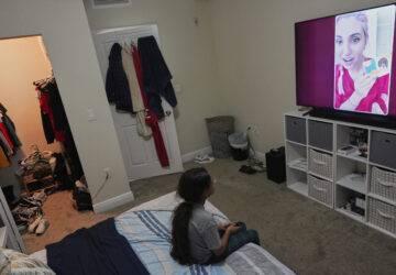 A 9-year-old girl with Temporary Protected Status, or TPS, who was born in Venezuela, but who fluently speaks only English and is in the gifted program at her school, watches TV in her family's apartment, Saturday, April 5, 2025, in Doral, Fla. (AP Photo/Rebecca Blackwell)
