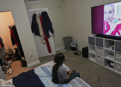 A 9-year-old girl with Temporary Protected Status, or TPS, who was born in Venezuela, but who fluently speaks only English and is in the gifted program at her school, watches TV in her family's apartment, Saturday, April 5, 2025, in Doral, Fla. (AP Photo/Rebecca Blackwell)