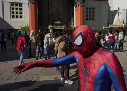 A street performer dressed as Spider Man walks past TCL Chinese Theatre on the Hollywood Walk of Fame in Los Angeles, Friday, April 4, 2025. (AP Photo/Jae C. Hong)