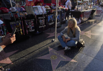 Silvia Camino, visiting from Argentina, takes photos with the Donald Trump star on the Hollywood Walk of Fame in Los Angeles, Friday, April 4, 2025. (AP Photo/Jae C. Hong)