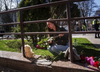 Kateryna Sitak, 23, a teacher, cries while laying flowers and toys on a site of a Russian missile strike in Sumy, Ukraine, Monday, April 14, 2025. (AP Photo/Evgeniy Maloletka)