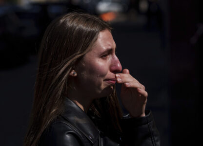 Kateryna Sitak, 23, a teacher, cries after laying flowers and toys on a site of a Russian missile strike in Sumy, Ukraine, Monday, April 14, 2025. (AP Photo/Evgeniy Maloletka)
