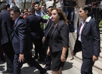 Peruvian President Dina Boluarte, center, is surrounded by security as she leaves the home of the late Peruvian Nobel literature laureate Mario Vargas Llosa, where she gave her condolences to his family the day after his death, in Lima, Peru, Monday, April 14, 2025. (AP Photo/Martin Mejia)