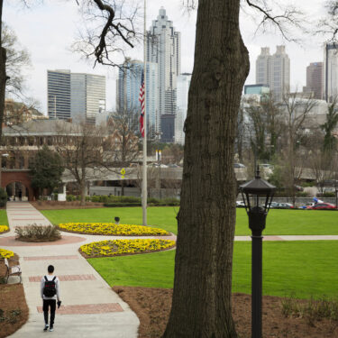 FILE - A person walks through the Georgia Tech campus with the downtown skyline in the background, March 11, 2016, in Atlanta. (AP Photo/David Goldman, File)