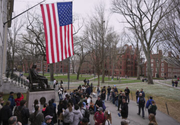 Visitors stop at the statue of John Harvard in Harvard Yard at Harvard University, Tuesday, April 15, 2025, in Cambridge, Mass. (AP Photo/Charles Krupa)