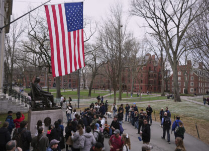 Visitors stop at the statue of John Harvard in Harvard Yard at Harvard University, Tuesday, April 15, 2025, in Cambridge, Mass. (AP Photo/Charles Krupa)