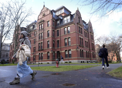FILE - People walk between buildings, Dec. 17, 2024, on the campus of Harvard University in Cambridge, Mass. (AP Photo/Steven Senne, File)