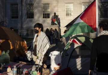 FILE - A student protester stands in front of the statue of John Harvard, the first major benefactor of Harvard College, draped in the Palestinian flag, at an encampment of students protesting against the war in Gaza, at Harvard University in Cambridge, Mass., April 25, 2024. (AP Photo/Ben Curtis, File)
