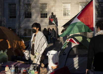 FILE - A student protester stands in front of the statue of John Harvard, the first major benefactor of Harvard College, draped in the Palestinian flag, at an encampment of students protesting against the war in Gaza, at Harvard University in Cambridge, Mass., April 25, 2024. (AP Photo/Ben Curtis, File)