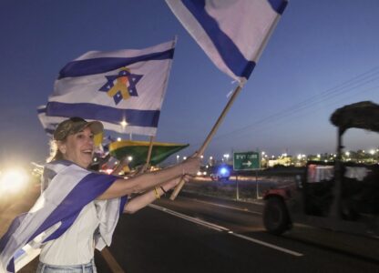 Amy Lieberman from Hillsdale, New Jersey, foreground, joins Israelis waving flags as the convoy carrying freed Israeli-American soldier Edan Alexander arrives after his release from Hamas captivity in Gaza to an army base in Reim, near the Gaza border, southern Israel, Monday, May 12, 2025.(AP Photo/Maya Alleruzzo)