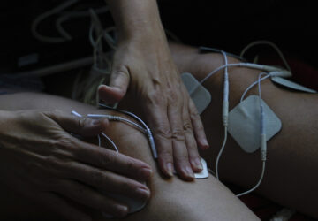 Priscilla Grim applies electrotherapy pads to her knees on April 18, 2025, at her apartment in New York. (AP Photo/Julia Demaree Nikhinson)