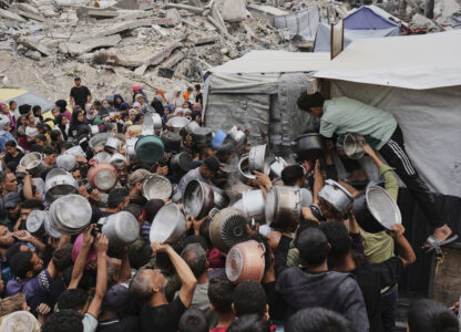 Palestinians struggle to get donated food at a community kitchen in Jabalia, northern Gaza Strip, Thursday, May 15, 2025. (AP Photo/Jehad Alshrafi)