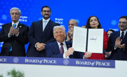 President Donald Trump, center, holds up a signed Board of Peace charter during the Annual Meeting of the World Economic Forum in Davos, Switzerland, Thursday, Jan. 22, 2026. (AP Photo/Evan Vucci)