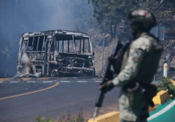 FILE - A soldier stands guard by a charred vehicle after it was set on fire, in Cointzio, Mexico, Feb. 22, 2026, following the death of the leader of the Jalisco New Generation Cartel, Nemesio Oseguera, known as 