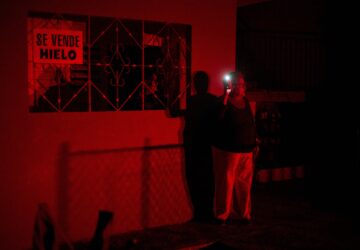 FILE - A woman holds up a cell phone flashlight as she chats with a friend during a scheduled power outage as part of energy rationing in Santa Cruz del Norte, home to one of Cuba's largest thermoelectric plants, Feb. 3, 2026. (AP Photo/Ramon Espinosa, File)