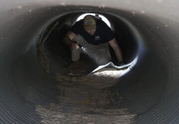 FILE - An investigator searches inside a culvert in the neighborhood where Annie Guthrie, whose mother Nancy Guthrie has been missing for more than a week, lives outside Tucson, Ariz., Feb. 10, 2026. (AP Photo/Ty ONeil, File)