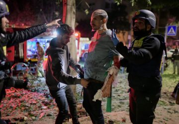FILE - Rescue workers bandage a wounded man and provide first aid at the site of a direct hit from an Iranian missile strike in Tel Aviv, Israel, Feb. 28, 2026. (AP Photo/Tomer Neuberg, File)