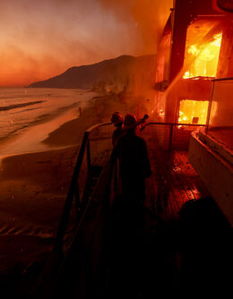 Firefighters work from a deck as the Palisades Fire burns a beachfront property in Malibu, Calif., Jan. 8, 2025. (AP Photo / Etienne Laurent)
