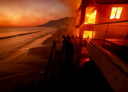 Firefighters work from a deck as the Palisades Fire burns a beachfront property in Malibu, Calif., Jan. 8, 2025. (AP Photo / Etienne Laurent)