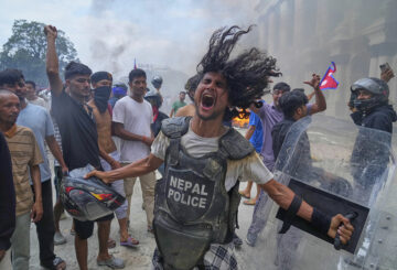 A protester wearing flak jacket and carrying a shield snatched from a policeman shouts slogans at the Singha Durbar, the seat of Nepal's government's various ministries and offices during a protest against social media ban and corruption in Kathmandu, Nepal, Sept. 9, 2025. (AP Photo / Niranjan Shrestha)
